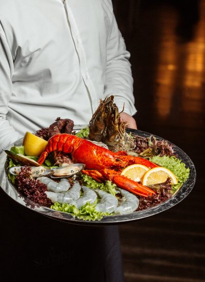 waiter holding seafood platter with lobster king prawns and mussels